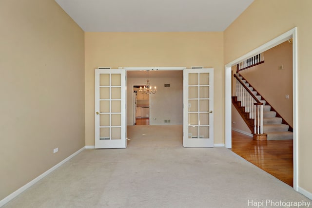 empty room featuring stairs, french doors, baseboards, and an inviting chandelier