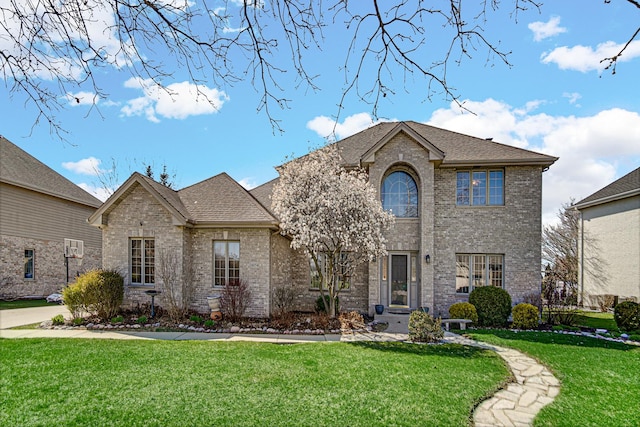 french country inspired facade featuring brick siding, a front lawn, and a shingled roof