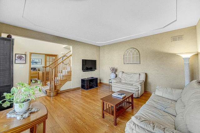 living room featuring stairs, light wood-style floors, and visible vents