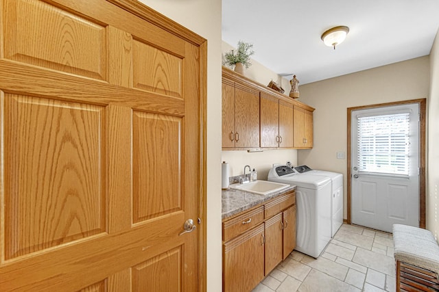 clothes washing area with cabinet space, washer and dryer, light tile patterned flooring, and a sink
