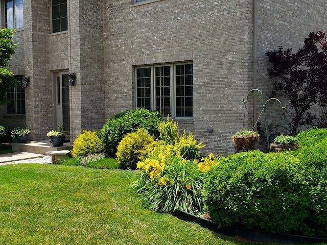 view of side of property with brick siding and a lawn