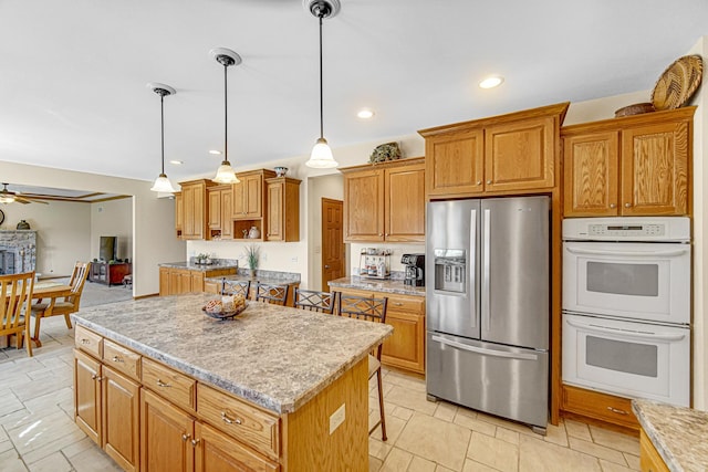 kitchen featuring a center island, stainless steel refrigerator with ice dispenser, ceiling fan, double oven, and pendant lighting