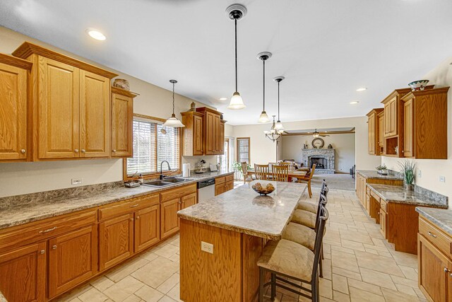 kitchen with dishwasher, a sink, a fireplace, a kitchen island, and a breakfast bar area