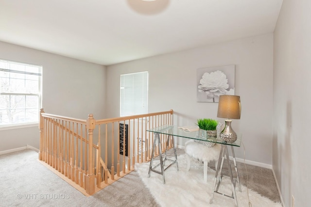 hall featuring carpet floors, baseboards, and an upstairs landing