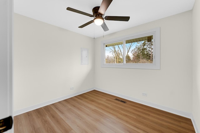 empty room with light wood-style floors, baseboards, a ceiling fan, and visible vents