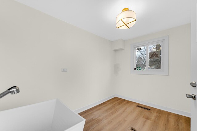 unfurnished room featuring light wood-style flooring, visible vents, baseboards, and a sink