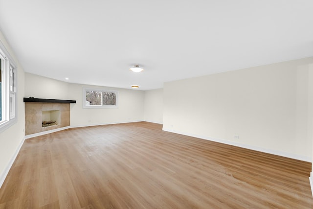 unfurnished living room with a fireplace, light wood-style floors, and baseboards