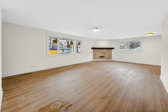 unfurnished living room featuring light wood-style flooring, a fireplace, and baseboards