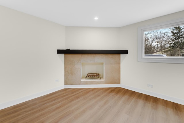 unfurnished living room featuring recessed lighting, a fireplace, baseboards, and wood finished floors