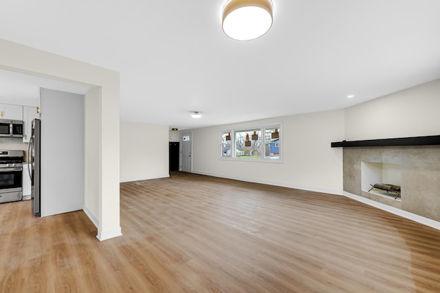 unfurnished living room featuring baseboards and light wood finished floors