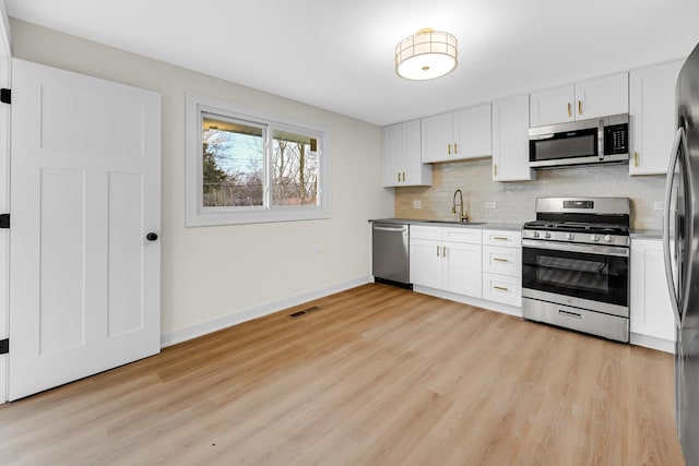 kitchen featuring tasteful backsplash, white cabinets, visible vents, a sink, and stainless steel appliances