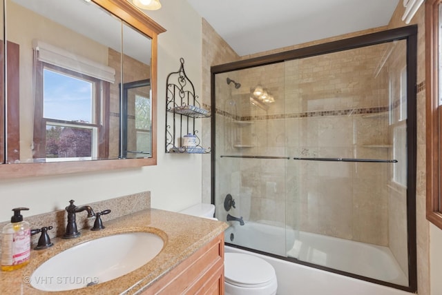 full bathroom with toilet, vanity, and bath / shower combo with glass door