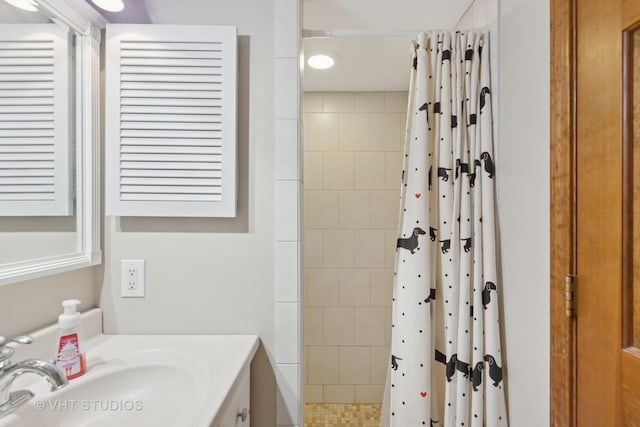 bathroom with a tile shower and vanity