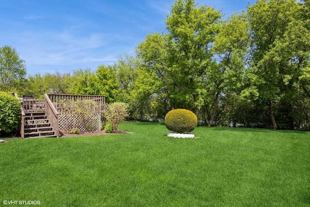 view of grassy yard with a wooden deck and stairway