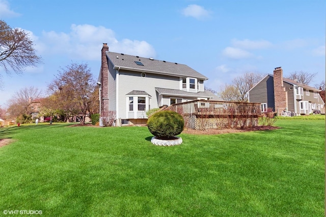 back of house featuring a wooden deck, a chimney, and a lawn