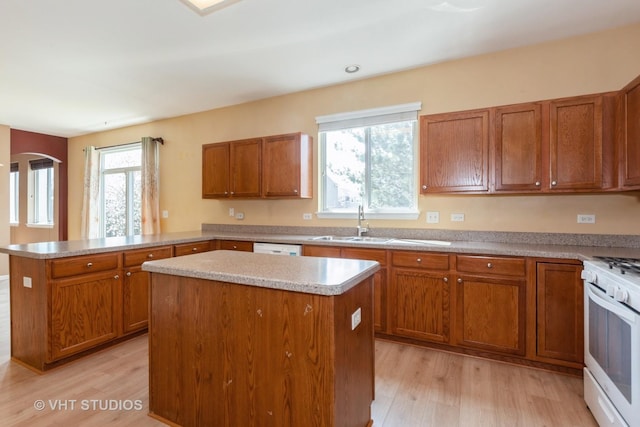 kitchen with brown cabinetry, light wood finished floors, and white appliances