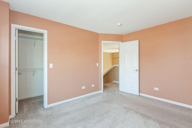 unfurnished bedroom with a spacious closet, baseboards, a closet, and carpet floors