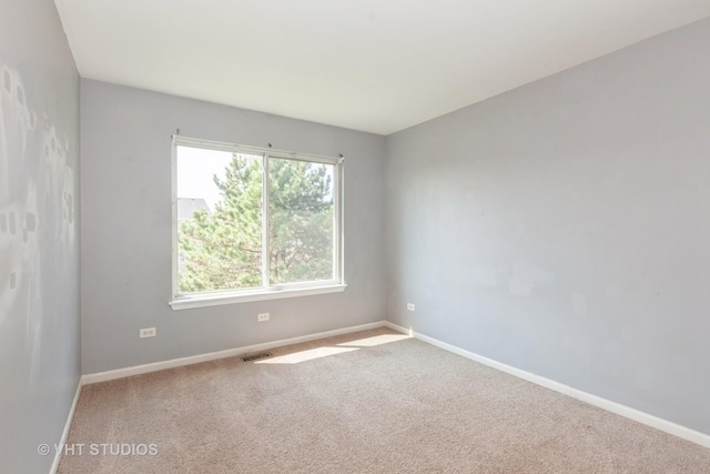 carpeted spare room with visible vents and baseboards