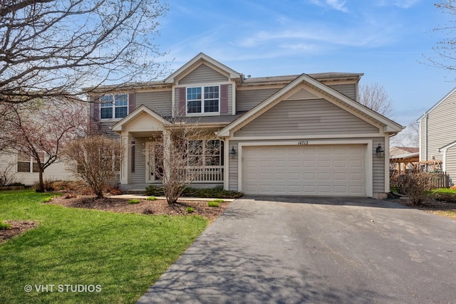 view of front of property with a front yard, driveway, an attached garage, and covered porch