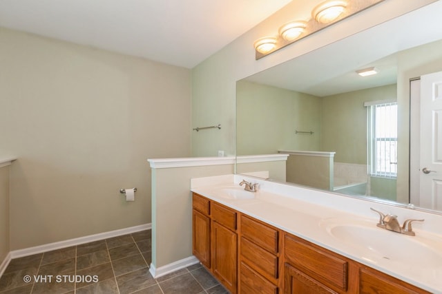 bathroom with double vanity, baseboards, and a sink