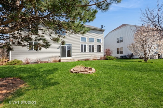rear view of property featuring a yard and a fire pit
