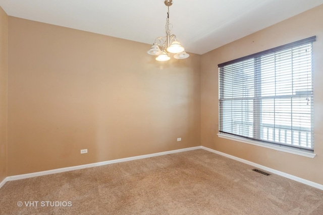 carpeted spare room featuring visible vents, baseboards, and an inviting chandelier