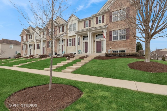 multi unit property with a residential view, a front lawn, and brick siding