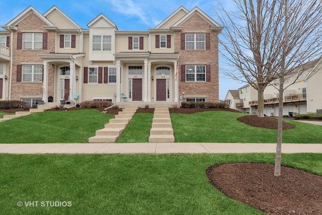 view of property featuring brick siding and a front lawn