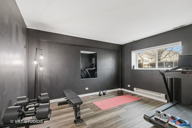 workout area with a baseboard radiator, wood finished floors, baseboards, and visible vents