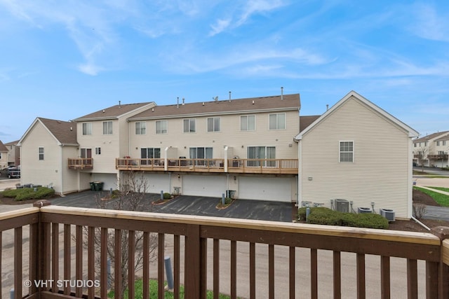exterior space featuring cooling unit, a balcony, an attached garage, driveway, and a residential view