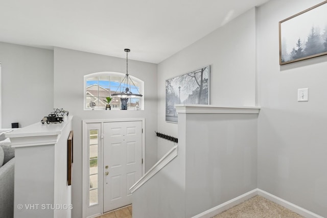 foyer entrance featuring a notable chandelier and baseboards