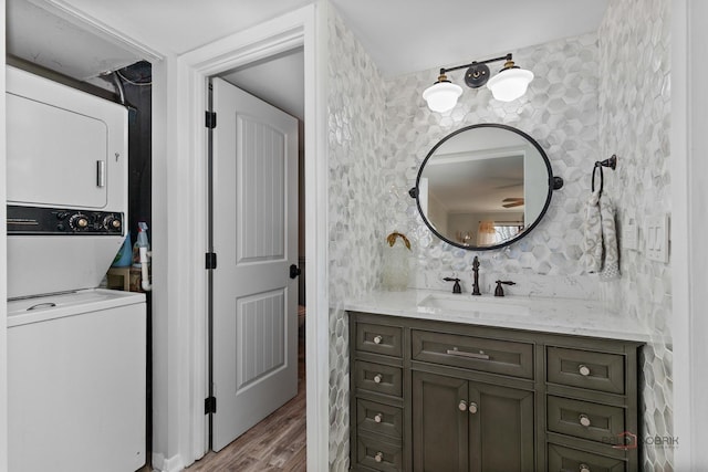 bathroom with vanity, wood finished floors, and stacked washing maching and dryer