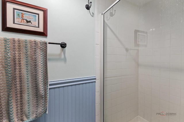bathroom with a wainscoted wall and a shower stall