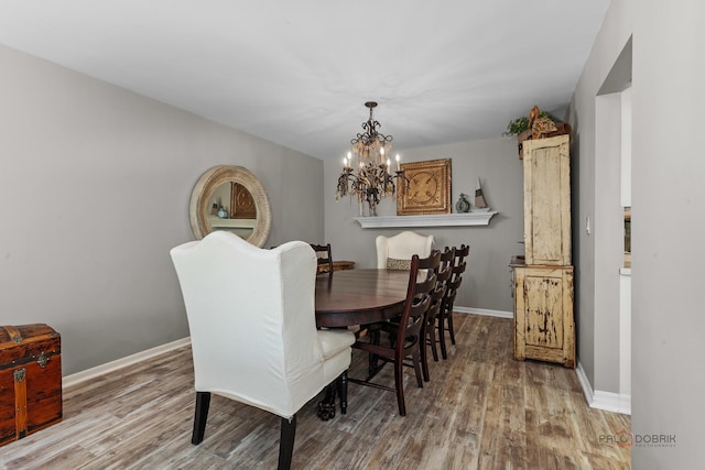 dining room featuring baseboards, a notable chandelier, and wood finished floors