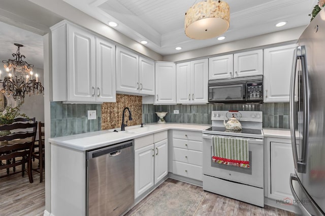 kitchen with a sink, light wood-type flooring, an inviting chandelier, light countertops, and appliances with stainless steel finishes