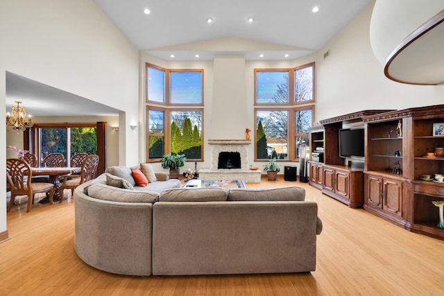 8209 N Oleander Ave, Niles, IL 60714 - living room with high vaulted ceiling, a chandelier, light wood-style flooring, a fireplace with raised hearth, and recessed lighting
