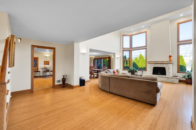 8209 N Oleander Ave, Niles, IL 60714 - living area with light wood-style floors, a chandelier, a towering ceiling, recessed lighting, and a stone fireplace