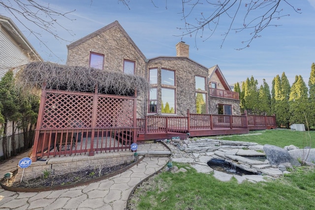 8209 N Oleander Ave, Niles, IL 60714 - rear view of house with a deck, a chimney, stone siding, and a lawn