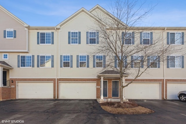 townhome / multi-family property with brick siding, driveway, and a garage