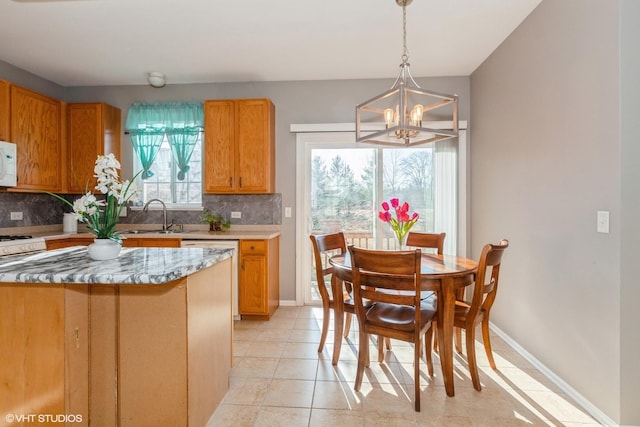 kitchen featuring white microwave, a chandelier, a sink, decorative backsplash, and baseboards