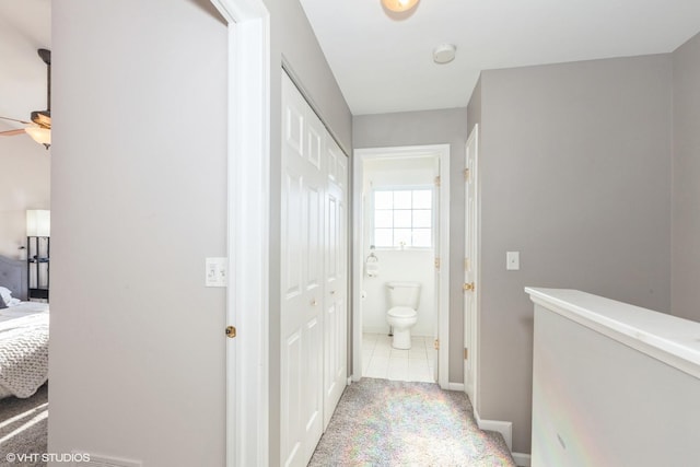 hallway with light carpet, light tile patterned floors, and baseboards