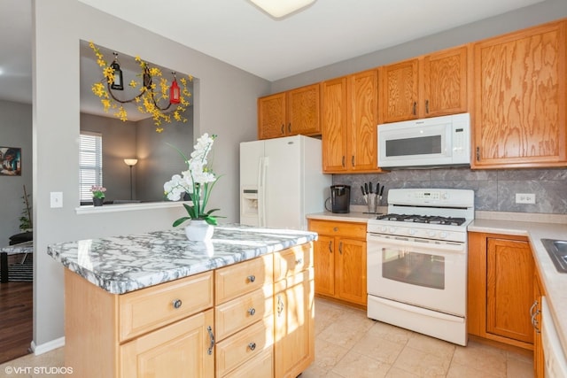 kitchen featuring backsplash, a center island, white appliances, and light stone countertops