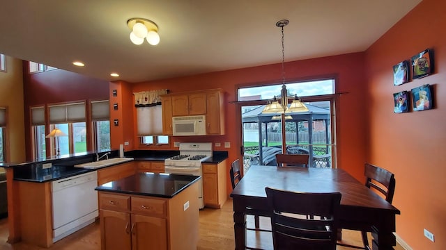 kitchen with a sink, dark countertops, a center island, white appliances, and a peninsula
