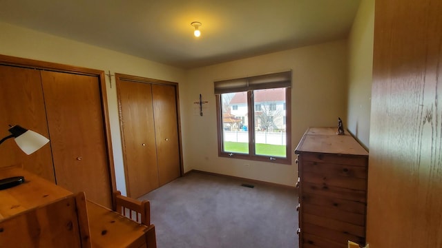 bedroom with visible vents, multiple closets, baseboards, and carpet floors