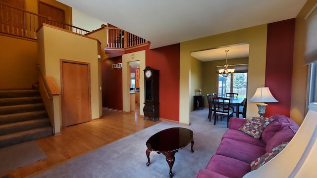 living room with wood finished floors, carpet flooring, baseboards, stairway, and a notable chandelier