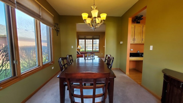 dining room featuring a notable chandelier, light carpet, and baseboards