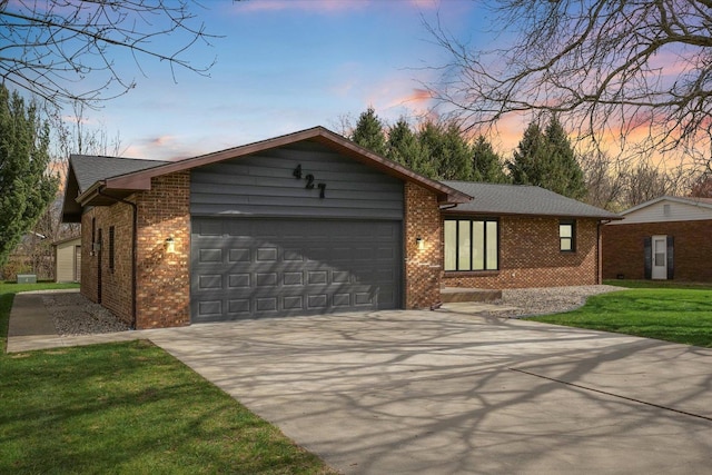 single story home featuring brick siding, a lawn, a garage, and concrete driveway