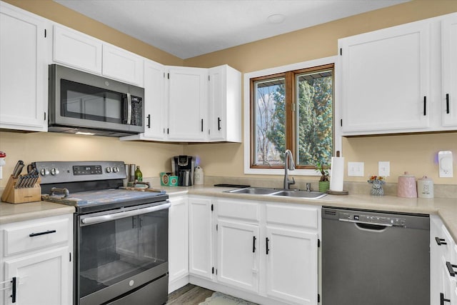 kitchen with light countertops, white cabinetry, a sink, and appliances with stainless steel finishes