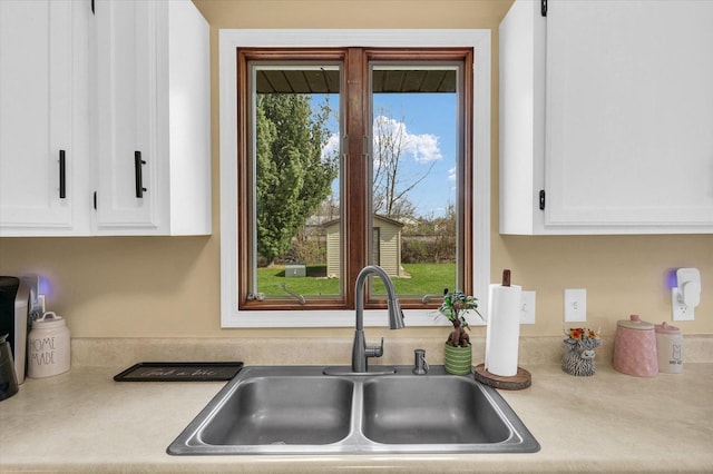 kitchen featuring light countertops, a sink, and white cabinetry