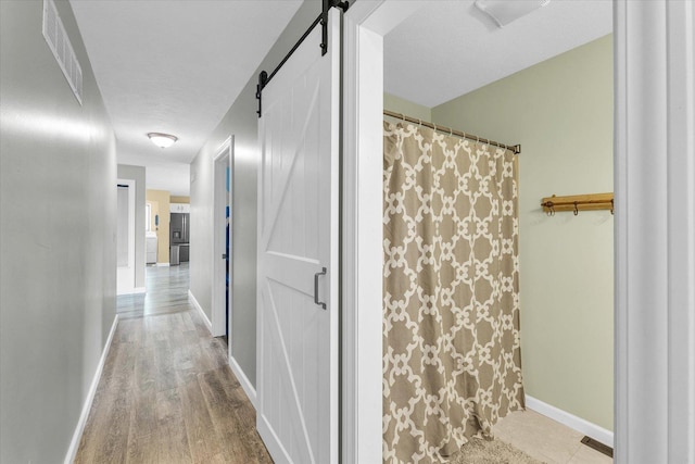 full bathroom with curtained shower, wood finished floors, baseboards, and visible vents